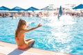 A lovely little girl sits on the side of the pool with her feet in the water enjoying the sun Royalty Free Stock Photo