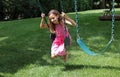 Lovely little girl at swings in the park with pink dress during summer in Michigan Royalty Free Stock Photo