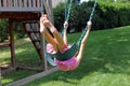 Lovely little girl at swings in the park with pink dress during summer in Michigan Royalty Free Stock Photo