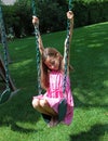 Lovely little girl at swings in the park with pink dress during summer in Michigan Royalty Free Stock Photo