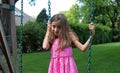 Lovely little girl at swings in the park with pink dress during summer in Michigan Royalty Free Stock Photo