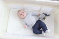 Lovely little 3 months girl with toy lying in travel crib