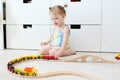 Lovely little 2 years girl playing toy wooden railroad at home