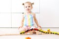 Portrait of lovely little 2 years girl playing toy wooden railroad at home