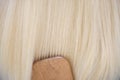 Lovely long blond hair combing with wooden massage comb close-up