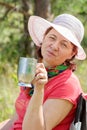 Lovely mature brunette cts in a lounge chair drinking coffee on a summer day.