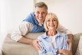 Lovely mature man embracing wife and smiling to camera Royalty Free Stock Photo