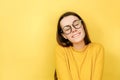 Lovely merry woman in eyeglasses has toothy smile, closes eyes, feels pleasure from good compliment, wears jumper