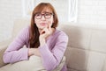 Lovely middle-aged brunette woman with glasses and smile sitting on sofa at home background. Menopause and mothers day. Mock up Royalty Free Stock Photo