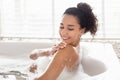 Lovely millennial woman lying in bathtub with foam, enjoying bubble bath, touching soft silky skin at hotel, free space Royalty Free Stock Photo