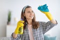 Lovely millennial woman in rubber gloves wiping window with spray detergent at home Royalty Free Stock Photo