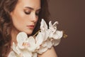 Lovely model woman with healthy clear skin and gentle orchid flowers. Facial treatment and skin care concept Royalty Free Stock Photo