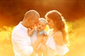 Lovely mom and dad with beautiful daughter at the park, young parents hold cute baby girl in tender arms, smile, enjoy