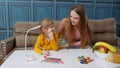 Lovely mother babysitter teacher helping kid daughter with homework, learning writing at home Royalty Free Stock Photo