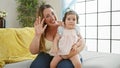Lovely mother confidently holding baby daughter in arms, enjoying a cheerful, casual chat on sofa Royalty Free Stock Photo