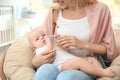 Lovely mother giving her baby drink from bottle in room Royalty Free Stock Photo