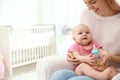 Lovely mother giving her baby drink from bottle in room Royalty Free Stock Photo