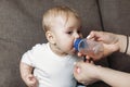 Lovely mother giving her baby drink juice from bottle Royalty Free Stock Photo