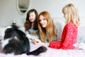 Lovely mother and two little girls daughters cuddling together with cat in bed in morning. Happy family of young single Royalty Free Stock Photo