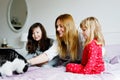 Lovely mother and two little girls daughters cuddling together with cat in bed in morning. Happy family of young single Royalty Free Stock Photo