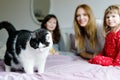 Lovely mother and two little girls daughters cuddling together with cat in bed in morning. Happy family of young single Royalty Free Stock Photo