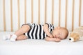 Lovely newborn baby in bodysuit napping in comfortable crib Royalty Free Stock Photo