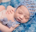 Lovely newborn in blue hat with little toy