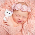 Lovely newborn girl holding toy on pink fluffy blanket