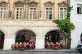 Lovely old street cafe full of people. The building is overgrown with plants. Prague location.