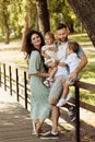 Lovely parents with little kids at the park, loving dad hold in arms adorable daughter and lovely son, happy mom smiling Royalty Free Stock Photo