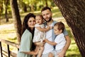 Lovely parents with little kids at the park, loving dad hold in arms adorable daughter and lovely son, happy mom smiling Royalty Free Stock Photo