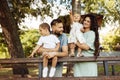 Lovely parents with little kids at the park, loving dad hold in arms adorable daughter and lovely son, happy mom smiling Royalty Free Stock Photo
