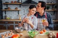 Lovely picture of man sitting with woman together at table in kitchen. He kiss her forehead and hold glass on wine in Royalty Free Stock Photo