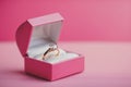 A pink gift box and engagement gold ring on a pink background