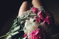 Lovely pink peonies on legs of boho girl in white bohemian dress