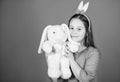 Lovely playful bunny child hugs soft toy. Bunny ears accessory. Bunny girl with cute toy on blue background. Child