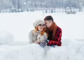 Lovely portrait of the beautiful happy loving couple hugging while leaning on the snow wall in the winter village. Royalty Free Stock Photo