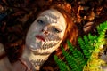 Lovely portrait of a young seductive foxy girl in autumn, with shadow of fern frond on face, beautiful sexy attractive redhead
