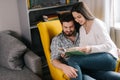 Lovely positive young couple reading a book together, sitting on yellow chair Royalty Free Stock Photo