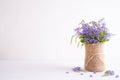Lovely purple flower in sack vase on white wooden table