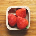 Lovely red fresh ripe strawberry in wood bowl on wooden table, copy space, 1:1 Royalty Free Stock Photo