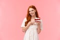 Lovely, romantic and alluring redhead girlfriend baked delicious surprise for valentines day date, holding peace cake on Royalty Free Stock Photo