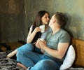 Lovely romantic couple going to kiss, look at each other as sit on bed, drink coffee Royalty Free Stock Photo