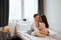 Lovely romantic man and woman going to kiss, look at each other as sit on bed Royalty Free Stock Photo