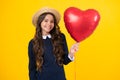 Lovely romantic teenage girl hold red heart balloon, symbol of love for valentines day  on yellow background. Royalty Free Stock Photo