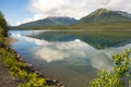 Mountains and trees reflected in a calm lake along the cassiar highway