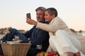 Lovely senior couple enjoying picnic at seashore in evening Royalty Free Stock Photo