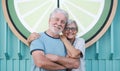 Lovely senior couple hugging and looking at camera standing in city street at sunset light Royalty Free Stock Photo