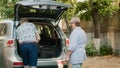 Lovely senior couple putting luggage in car trunk Royalty Free Stock Photo