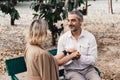 Lovely senior elderly smiling couple man and woman holding hand as promising of forever love or take care in romantic moment. Warm